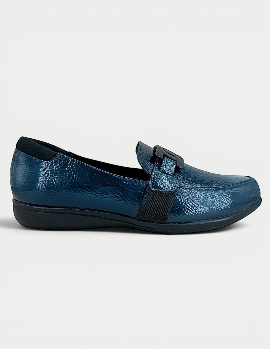 Mocasín Manet azul marino brillante con detalle de hebilla y banda elástica. Diseño clásico y cómodo para uso diario.